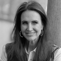 Black and white professional headshot of Cindy Dunkle, smiling and wearing a blazer, white blouse, and pearl necklace.