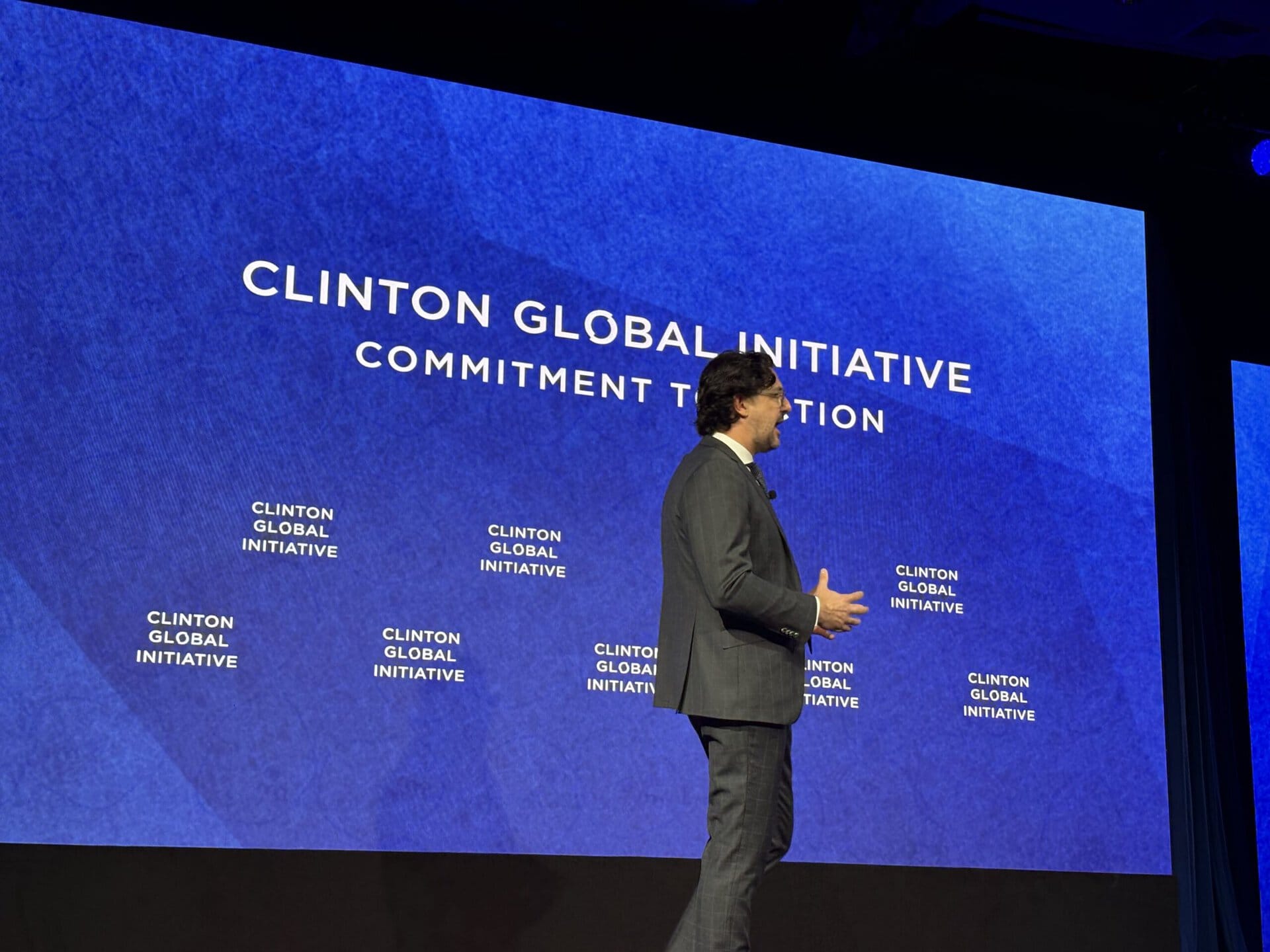 Speaker at Clinton Global Initiative event with blue background and logo.